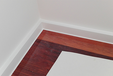 Schilderafwerking binnen aan de plinten met houten gekleurde vloer.